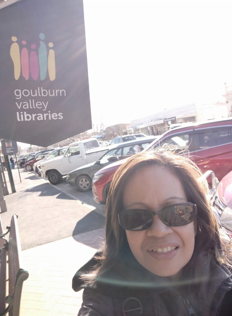 Female infront of Goulbourn Valley Libraries sign