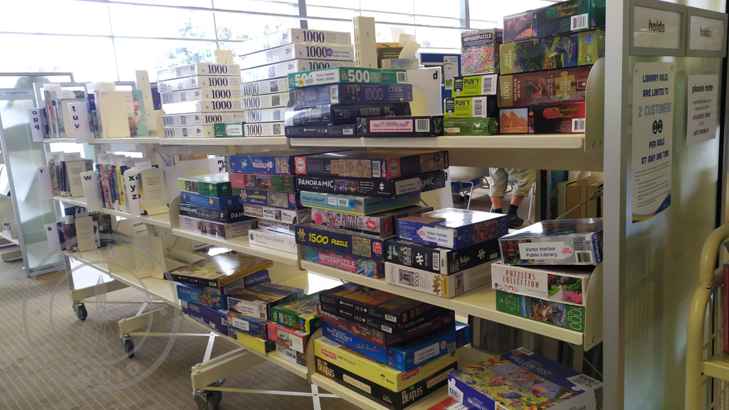 inside Victor Harbor Library looking at boxes of puzzles on selves